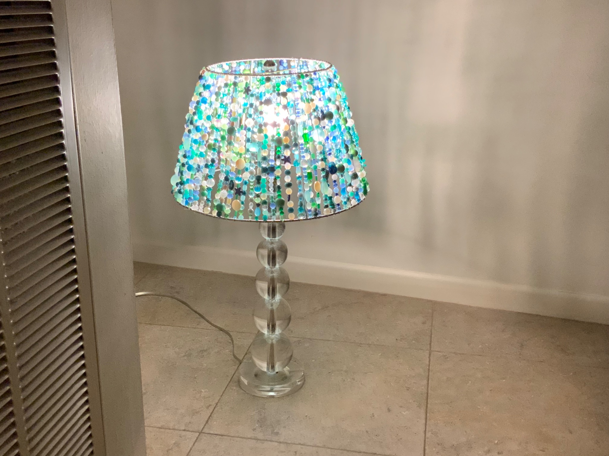 Completed blue green Beaded Light illuminated on clear glass base
